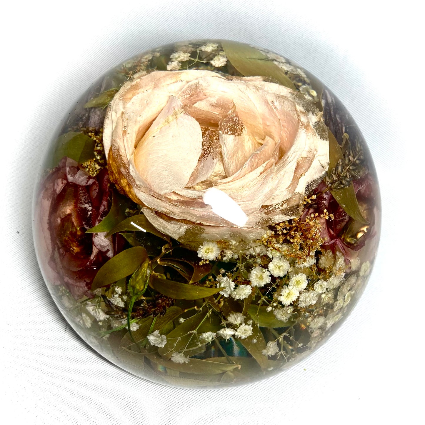 A stunning wedding bouquet preserved inside a large clear resin sphere. The delicate flowers, leaves, and stems are perfectly encased, creating a timeless and unique display piece. Perfect for reliving special memories and adding a touch of elegance to any room.