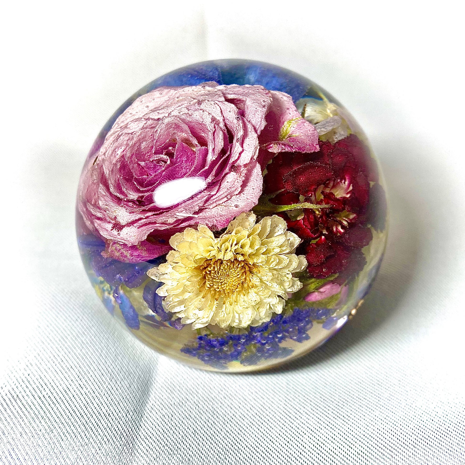 A decorative sphere paperweight made of resin, showcasing beautifully preserved wedding flowers, adding a unique and memorable touch to any space.