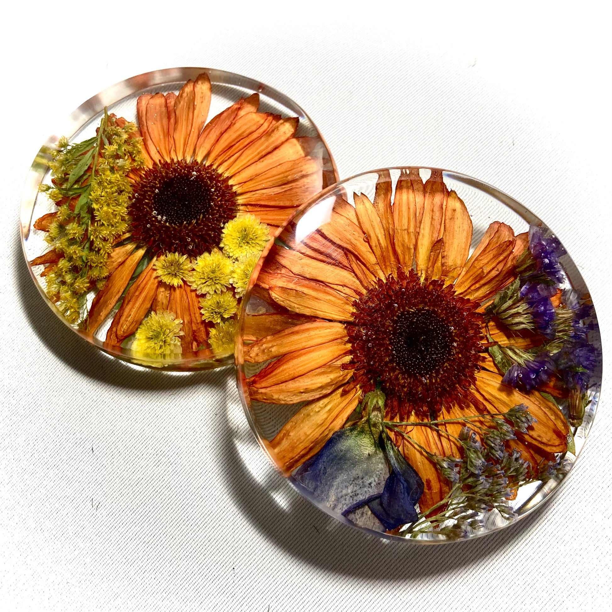 A clear, resin coaster featuring preserved wedding flowers encased within its surface. The round coaster showcases a bouquet of delicate blooms in vibrant colors, adding a touch of elegance to any tabletop.