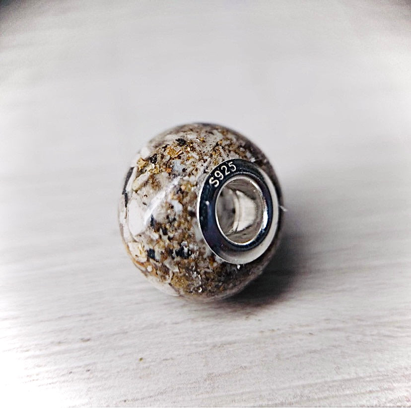 Round, translucent resin cremation bead Featuring a natural ash look. The bead is smooth to the touch and contains a small amount of ashes from a loved one.