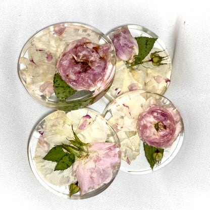 A clear, resin coaster featuring preserved wedding flowers encased within its surface. The round coaster showcases a bouquet of delicate blooms in vibrant colors, adding a touch of elegance to any tabletop.