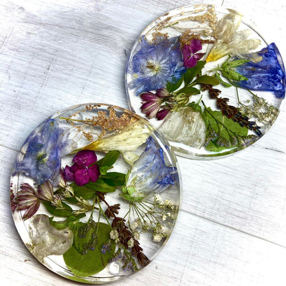 A clear, resin coaster featuring preserved wedding flowers encased within its surface. The round coaster showcases a bouquet of delicate blooms in vibrant colors, adding a touch of elegance to any tabletop.