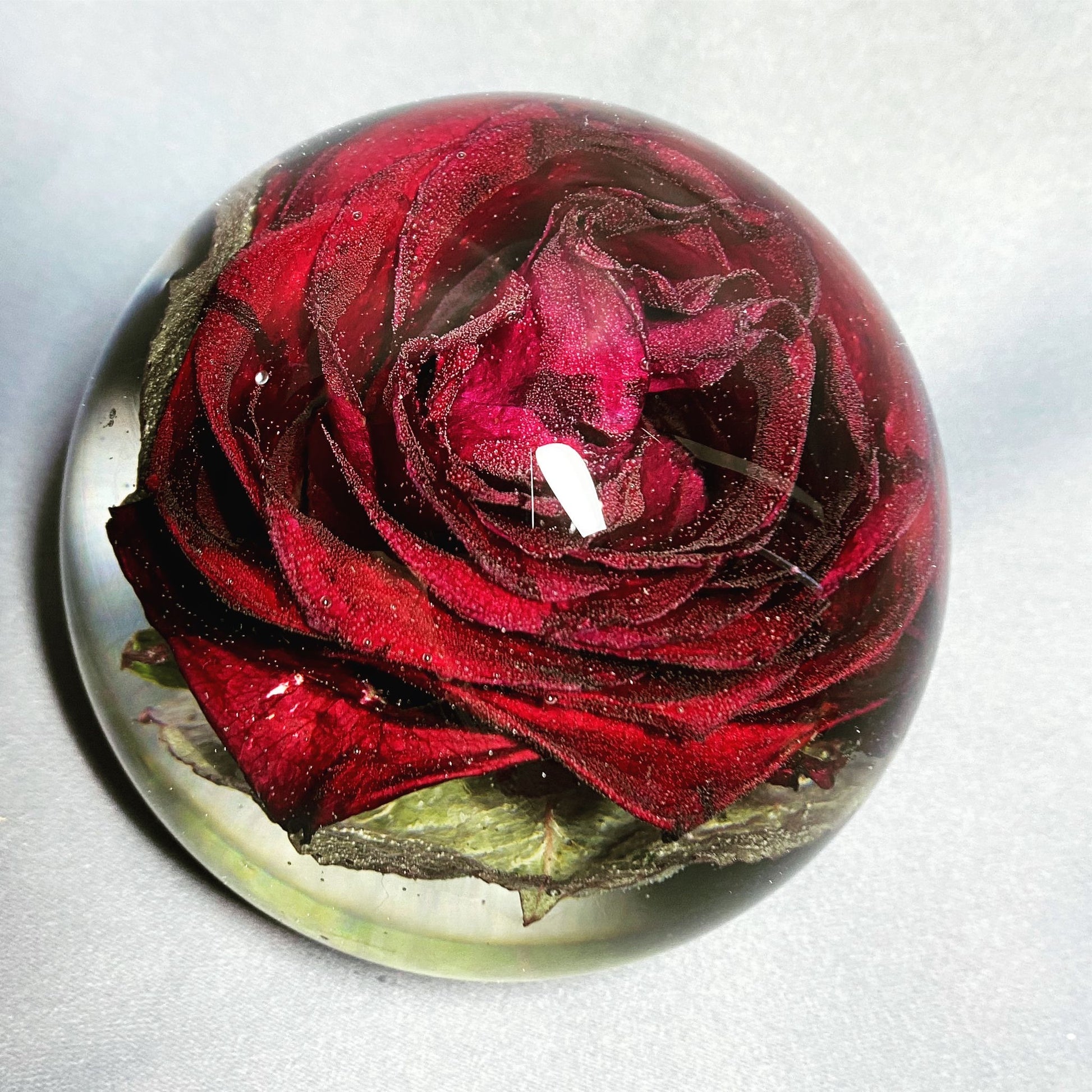 A decorative sphere paperweight made of resin, showcasing beautifully preserved wedding flowers, adding a unique and memorable touch to any space.
