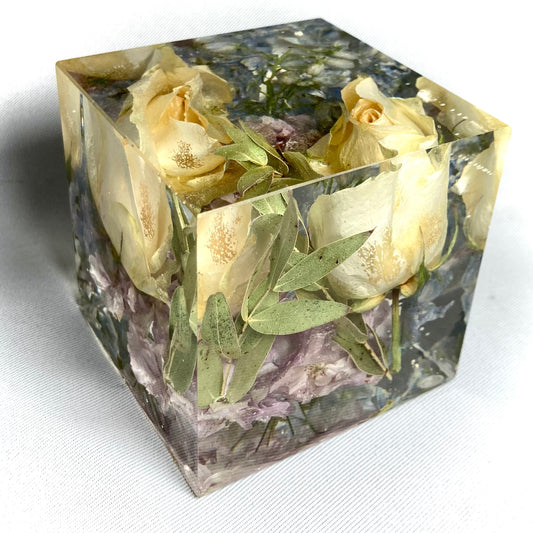 8cm cube containing two small peach roses, pale blue delphinium pink blossom