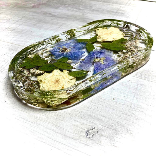 Oval jewellery tray containing delphinium and pressed white roses and foliage