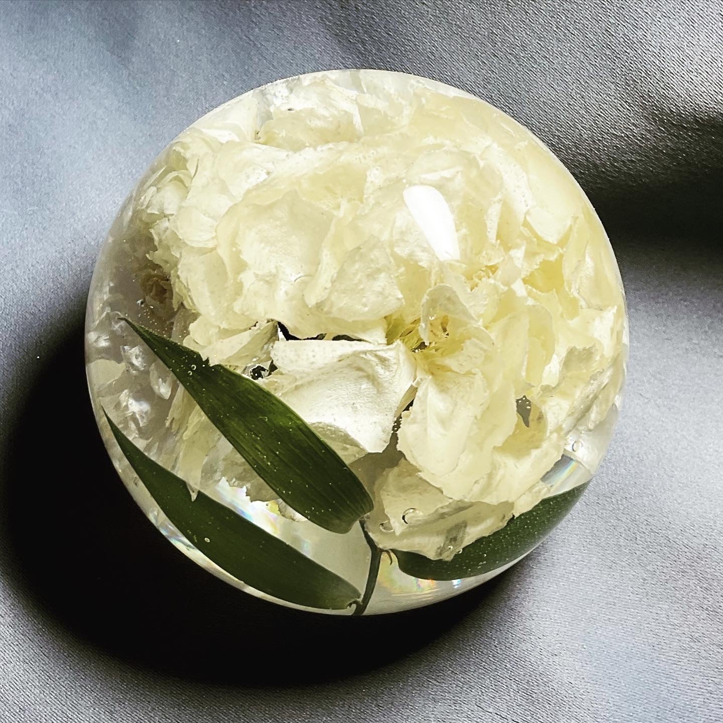 A decorative sphere paperweight made of resin, showcasing beautifully preserved wedding flowers, adding a unique and memorable touch to any space.,