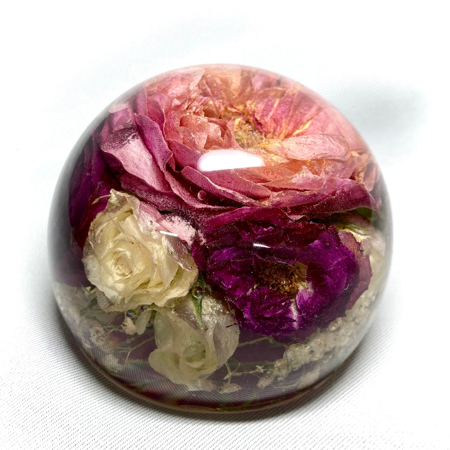 11cm flat bottom sphere containing a mixture of pink and white spray roses, large peach variegated rose, gypsophila and foliage
